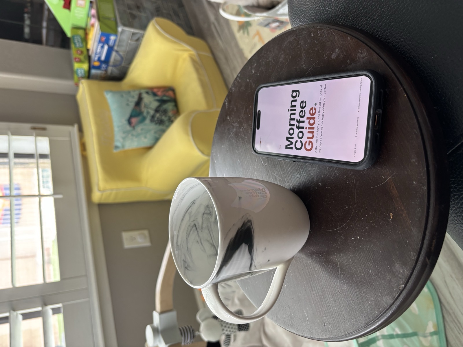 The Morning Coffee Guide PDF open on a phone, held in one hand beside a coffee mug